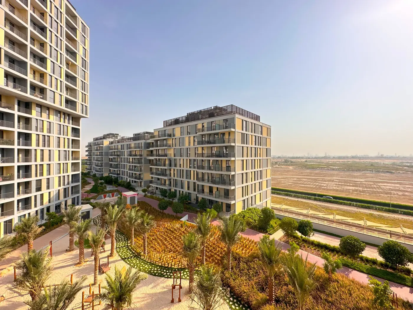 Noor buildings and gardens at Midtown, with the open land of Dubai Production City behind