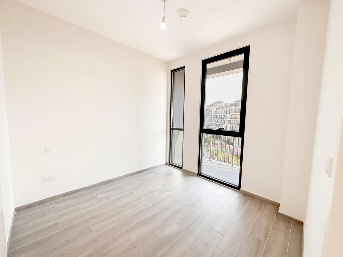 Bedroom with a full-height window and balcony door in a Noor apartment